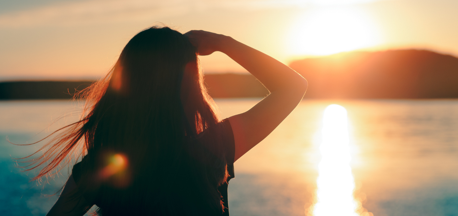 A woman looking out over the horizon at sunset.