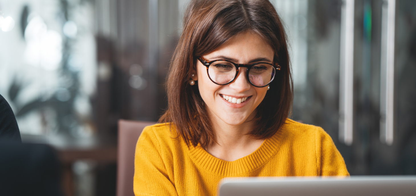 Photo of a smiling woman working on her laptop.