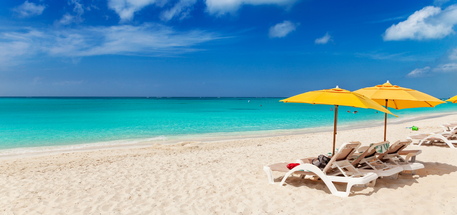 Two beach chairs and two yellow umbrellas on a beach.